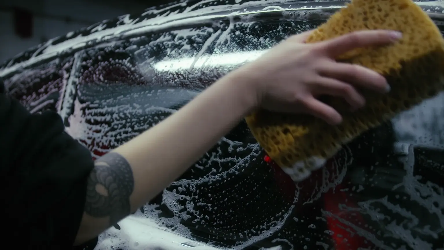 Lavage à la main d’une voiture noire couverte de mousse